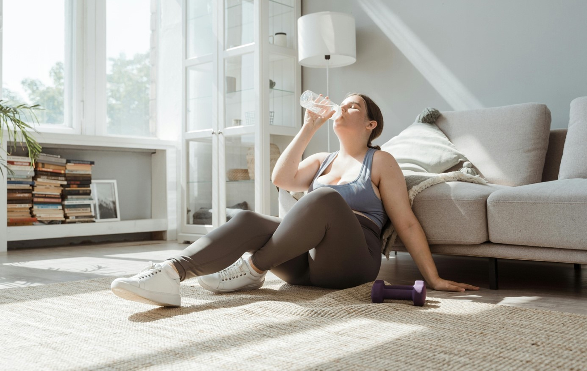 Eine Frau erholt sich nach dem Training zu Hause – regelmäßige Bewegung unterstützt die Lebergesundheit und kann einer MASH-Leber vorbeugen. 